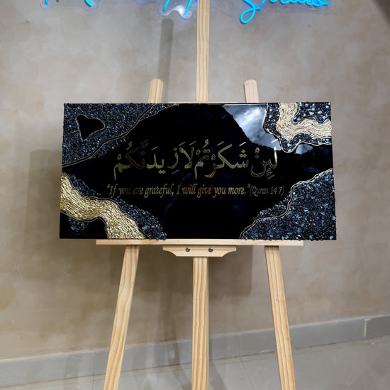 Handcrafted La'in Shakarthum Islamic resin wall art in black and gold, 70 × 35 cm, made with Jet Black pigment and a glossy epoxy resin finish.