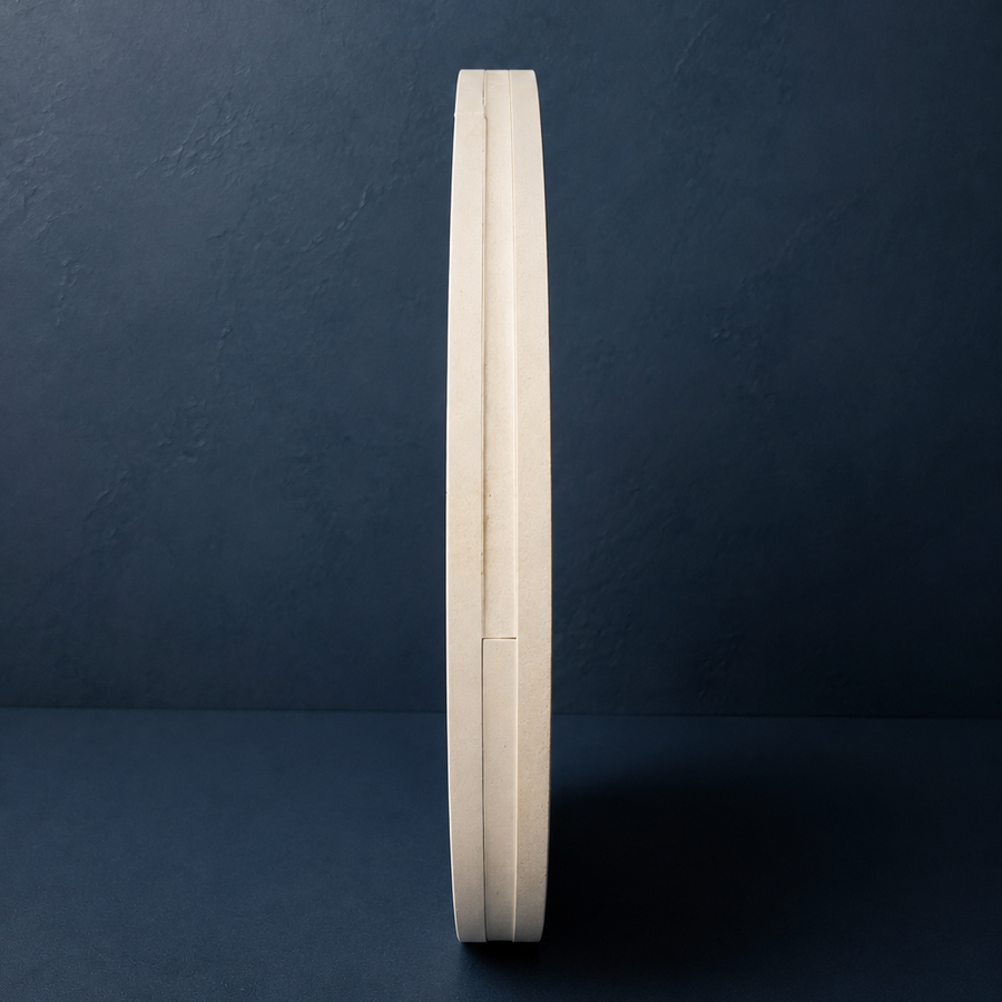A minimalist, circular wall clock with a light beige wood-grain frame and a dark face, shown in profile against a dark textured blue background.